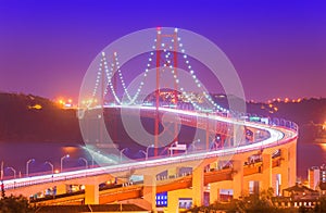 View of The 25th April Bridge Ponte 25 de Abril with car light trails in haze. Popular landmark of Lisbon, Portugal