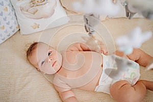 view from above. a baby lies in a white crib with mobile with toys.