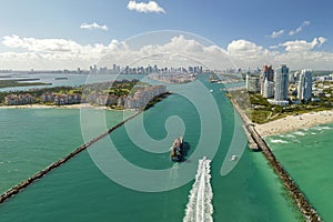 View from above of big container ship entering main channel in Miami harbor near South Beach high luxurious hotels and
