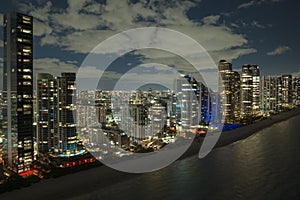 View from above of brightly illuminated high skyscraper buildings in downtown district of Sunny Isles Beach city in