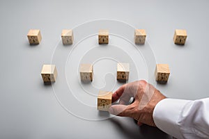 View from above of a businessman arranging wooden cubes with people icon