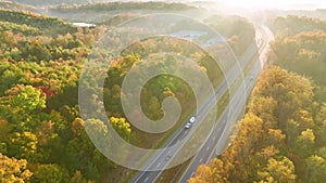 View from above of busy american highway with fast moving traffic between autumn woods. Interstate transportation