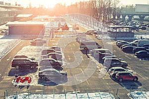 View from above on car parking with many vehicles and free lots at bright early frosty cold winter morning. Parking lot with