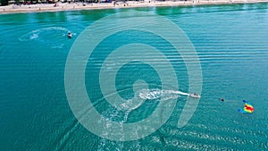 View from above of clear sea water with staff and tourists heading to boat after finished parasailing