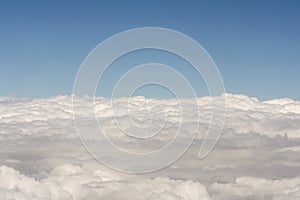 View of above clouds from airplane with blue sky background