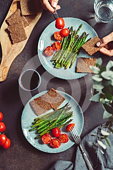 View from above on dinner for two people, grill asparagus and cherry tomatoes