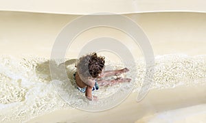 View from Above of a diverse boy riding down a water slide