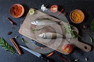 View from above of fish with vegetables and spices on a wooden board