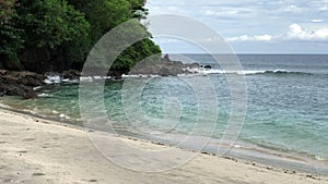 view from above of giant ocean waves crashing and foaming on empty sand tropical beach with big rock stones. shot of