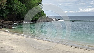 View from above of giant ocean waves crashing and foaming on empty sand tropical beach with big rock stones. shot of