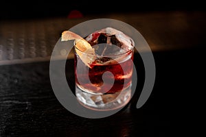 View from above glass of a Boulevardier cocktail with orange zest on the steel wooden bar counter