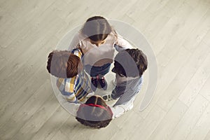 View from above of group of little children standing close in circle and holding hands