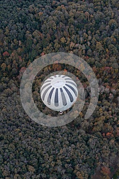 View from above of a hot air balloons flying over pinewood forest at La Garrotxa Volcanic Natural Park.