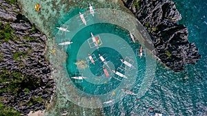 A view from above on a lagoon in which boats brought tourists for a rest. Aerial view of the turquoise water between the black st