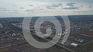 View from above of large industrial area located outside the city with fields and trees on the background against cloudy