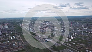 View from above of large industrial area located outside the city with fields and trees on the background against cloudy