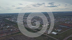 View from above of large industrial area located outside the city with fields and trees on the background against cloudy