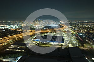 View from above of many parked cars on illuminaded parking lot at night in front of a superstore. Place for vehicles in