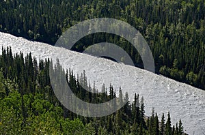 View from above of the Matanuska River  on the banks of which is dense forest.