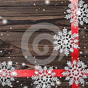 View from above of a Merry Christmas inscription on dark brown wooden background with red ribbon and handmade tree toys star