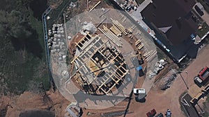 View from above of new wooden cottage building in progress, construction machinery, workers and construction materials
