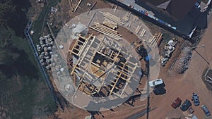 View from above of new wooden cottage building in progress, construction machinery, workers and construction materials