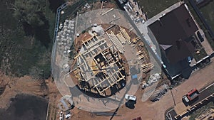 View from above of new wooden cottage building in progress, construction machinery, workers and construction materials