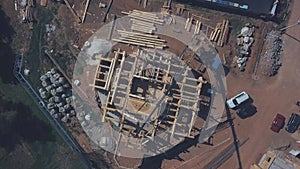 View from above of new wooden cottage building in progress, construction machinery, workers and construction materials