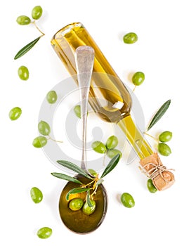 View from above of a olive oil in bottle, in a spoon and raw olives