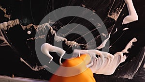 View from above an orange glove with a metal scraper smears detergent on a ceramic electric stove. Close-up.