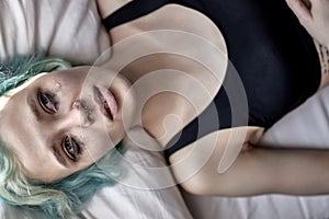 View From above On Pensive sad young caucasian woman lying on bed pondering thinking