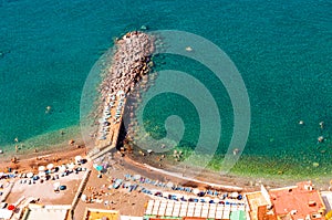 View from above on rocky stones marinas on the beach full of tourists, deckchairs, umbrellas on Tyrrhenian sea bay near Meta and