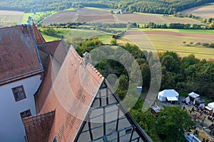 View from above of the roof of an old castle, landscape and tents in the forecourt photo