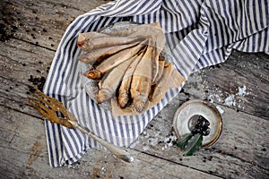 View from above on the smoke-dried fish on plate on a baking paper on the grey striped napkin with a decorate golden