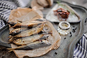 View from above on the smoke-dried horse mackerel fish on the paper on the metal tray with a sun dried tomatoes, oil and