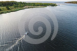 Aerial view of sailing white yacht in sea next to a green coastline