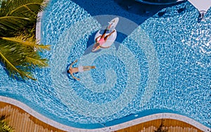 View from above at a swimming pool, couple men and women in swimming pool, drone view