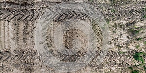 view from above on texture of wet muddy road with tractor tire tracks in countryside