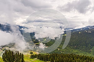 View from above on thick, fluffy white clouds over wooded mountains with country roads