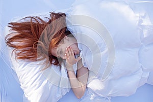 View from above to an attractive, young, sexy red haired, yawning woman, enjoys the bed, in the morning sun, copy space