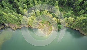 View for above. Top view of lake surrounded by mountains and pine forest