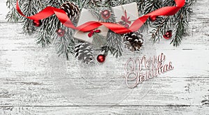 View from above, top, on a white wooden board background with fir branch with pines, present boxes, ribbon, red tree globes