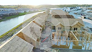 View from above of unfinished frames of inexpensive homes with wooden roof beams under construction. Development of