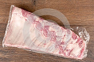 View from above of vacuum-packed pork ribs on a wooden table.