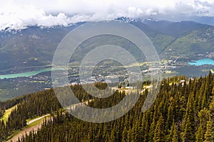 view from above of a village in the mountains between two lakes, surrounded by a dense coniferous forest