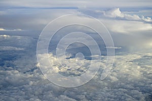 View of abstract soft white cloud shape with shades of blue sky background from above flying plane window