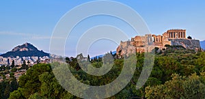 View of Acropolis hill and Lycabettus hill in background in Athens, Greece from Pnyx hill in soft summer sunset sky.