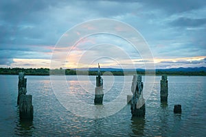 View across bay and old wharf posts at dusk on cloudy evening