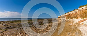 A view across the beach and along the white, red and orange stratified cliffs at Old Hunstanton, Norfolk, UK