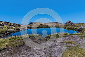 A view across Doxey Pool looking towards the cliff edge on the summit of the Roaches escarpment, Staffordshire, UK